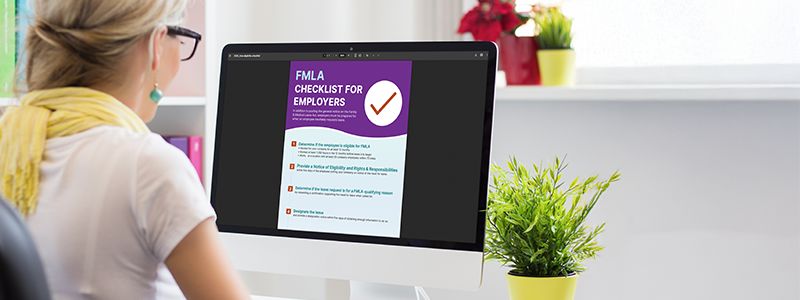 Person viewing an “FMLA Checklist for Employers” on a computer screen, with key steps like eligibility determination and leave designation visible.